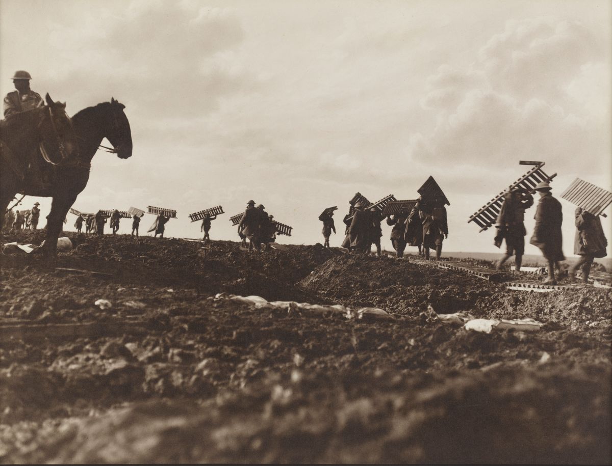Carrying duckboard sections forward to make a track through the mud (Frank Hurley — State Library of NSW)